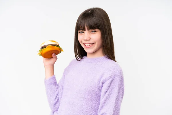 Pequeña Chica Caucásica Sosteniendo Una Hamburguesa Sobre Fondo Aislado Sonriendo — Foto de Stock