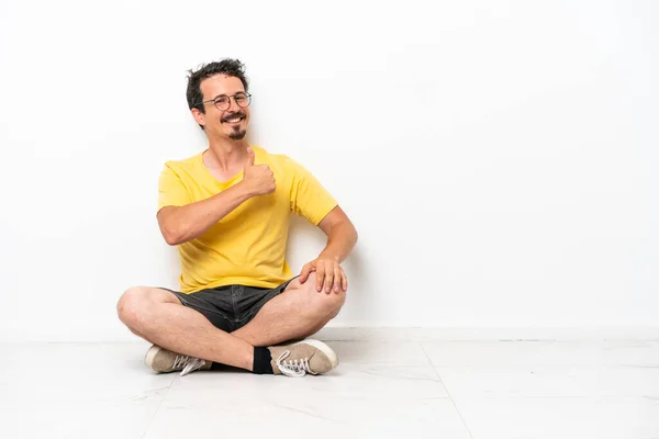 Joven Hombre Caucásico Sentado Suelo Aislado Sobre Fondo Blanco Dando — Foto de Stock