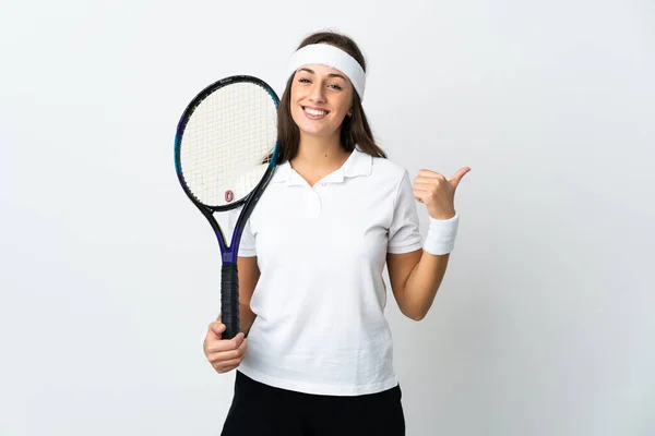 年轻的女网球选手在孤立的白色背景下指着旁边展示一种产品 — 图库照片