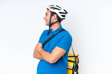 Beyaz arka planda, termal sırt çantalı beyaz tenli genç bir adam var.