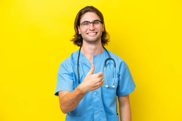 年轻的外科医生在黄色背景下被隔离的高加索男子举起了一个大拇指 — 图库照片