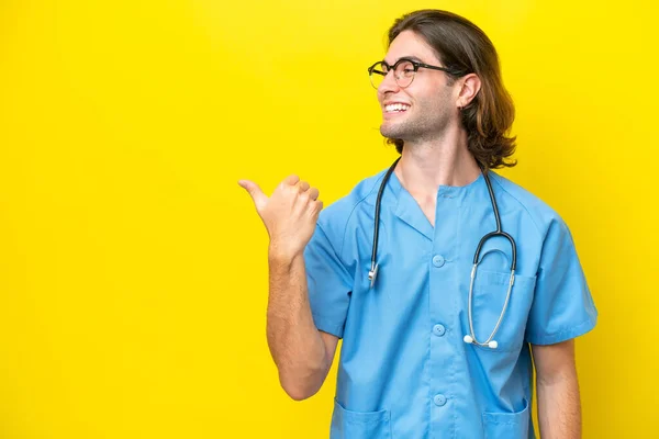Young Surgeon Caucasian Man Isolated Yellow Background Pointing Side Present — Stock Photo, Image