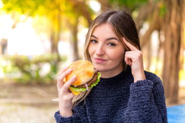 Genç ve güzel Romen kadın elinde hamburgerle