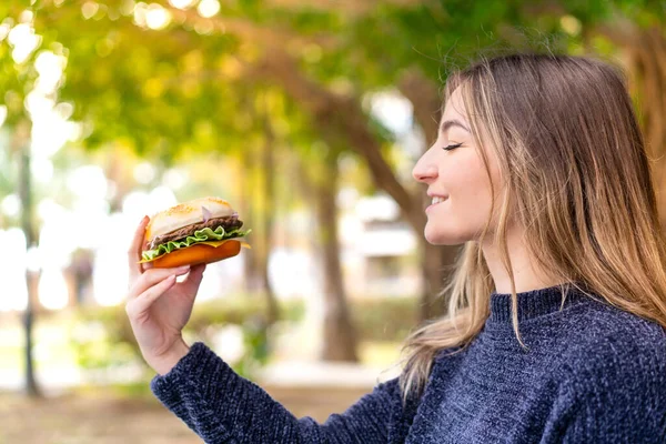 Młoda Ładna Rumuńska Kobieta Trzyma Hamburgera Świeżym Powietrzu Szczęśliwą Ekspresją — Zdjęcie stockowe