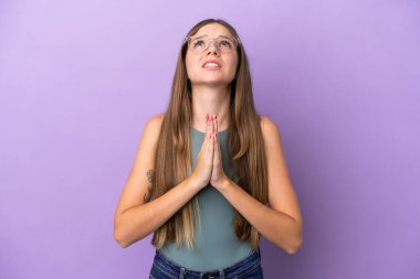 Mor arka planda izole edilmiş genç Litvanyalı kadın avuç içlerini bir arada tutuyor. İnsan bir şey ister.