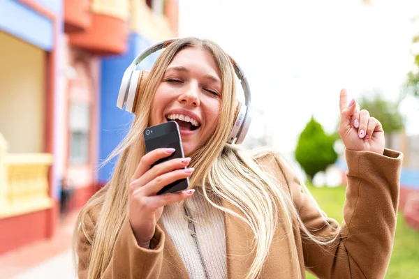 Молодая Красивая Блондинка Открытом Воздухе Слушает Музыку Мобильного Телефона Поет — стоковое фото