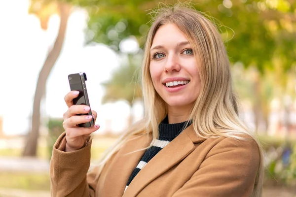 Joven Mujer Rubia Bonita Aire Libre Sosteniendo Teléfono Móvil Con —  Fotos de Stock