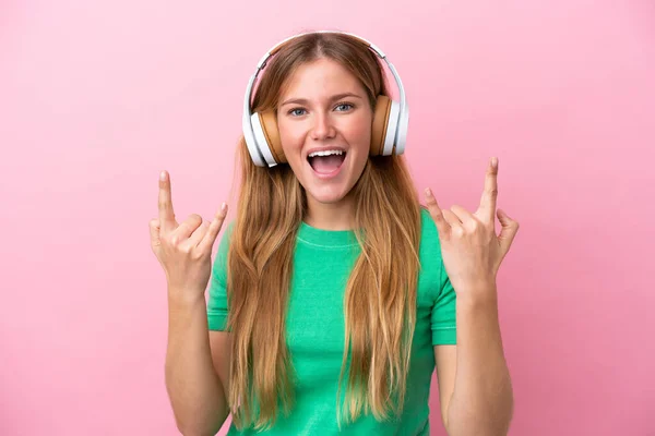 若いですブロンド女性絶縁上のピンクの背景リスニング音楽作る岩ジェスチャー — ストック写真