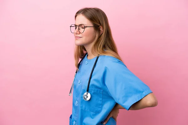 一位年轻的外科医生妇女 因努力工作而因粉红背景而遭受背痛之苦 — 图库照片