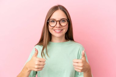 Genç Litvanyalı kadın pembe arka planda izole edilmiş gözlüklü ve başparmağıyla