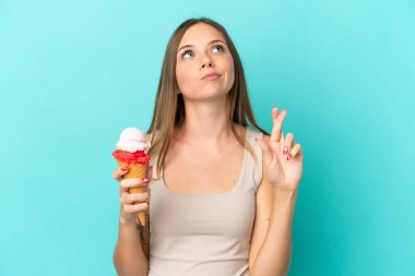 Kornet dondurmalı genç Litvanyalı kadın mavi arka planda izole edilmiş ve şans diliyor.