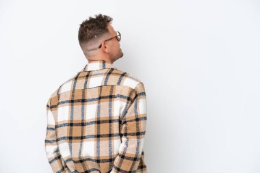 Beyaz arka planda beyaz tenli yakışıklı bir adam izole edilmiş ve arkasına bakıyor.