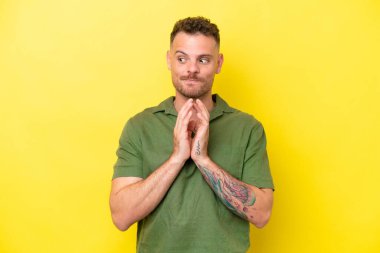 Beyaz tenli yakışıklı bir adam sarı arka planda izole edilmiş bir şeyler çeviriyor.