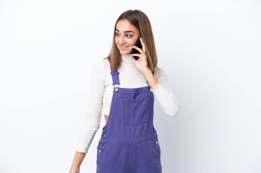 Beyaz arka planda izole edilmiş genç beyaz bir kadın cep telefonuyla sohbet ediyor.