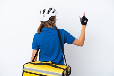 Beyaz arka planda izole edilmiş termal sırt çantalı beyaz kadın işaret parmağıyla işaret ediyor.