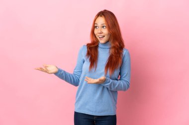 Teenager Russian girl isolated on pink background with surprise expression while looking side