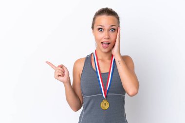 Beyaz arka planda izole edilmiş madalyalı genç Rus kız şaşırmış ve parmağıyla kenarı işaret ediyor.
