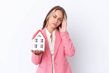 Rus emlakçı elinde oyuncak bir ev tutuyor. Beyaz arka planda, baş ağrısıyla izole edilmiş.