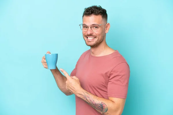Молодий Білий Чоловік Тримає Чашку Кави Ізольовано Синьому Фоні Вказує — стокове фото