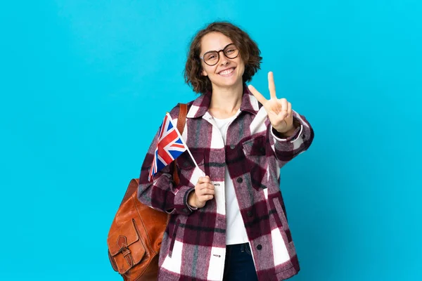 Молодая Английская Женщина Флагом Великобритании Синем Фоне Улыбается Показывает Знак — стоковое фото