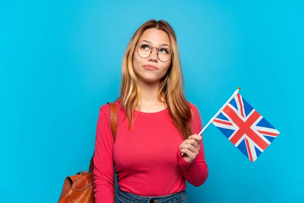 年轻女孩举着英国国旗 身披孤立的蓝色背景 抬头仰望 — 图库照片