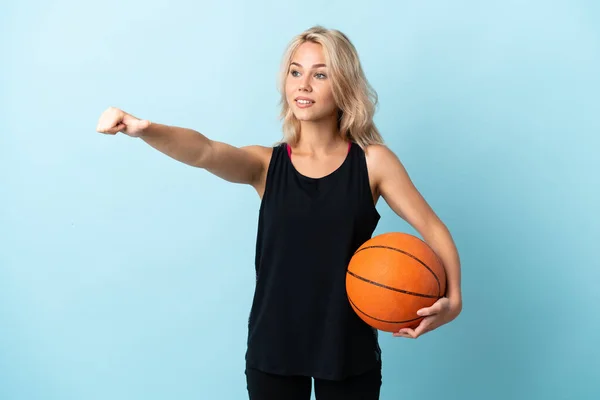 若いですロシアの女性遊びバスケットボール隔離された上の青の背景与えますA親指アップジェスチャー — ストック写真