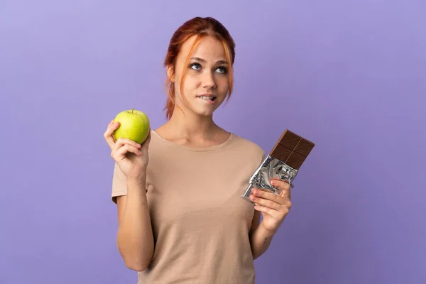 Teenager Ruské Dívka Izolované Fialovém Pozadí Pochybnostmi Při Užívání Čokoládové — Stock fotografie