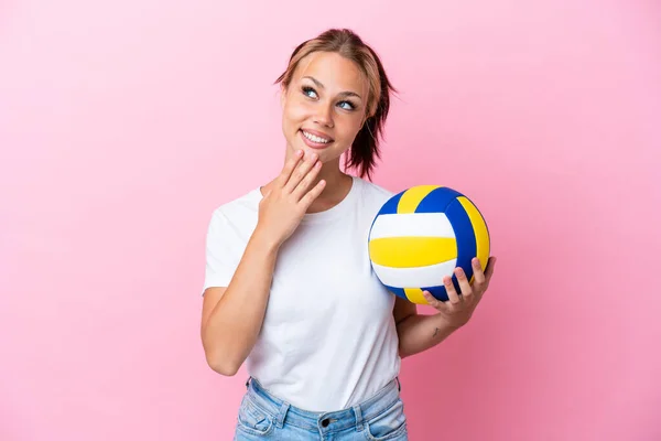 年轻的俄罗斯女子打排球时 背靠粉色背景 面带微笑地抬起头 — 图库照片