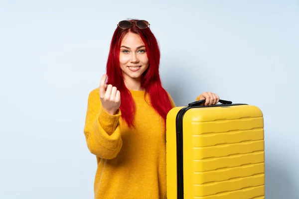 带着一个蓝色背景的手提箱的旅行女孩来做手势 — 图库照片