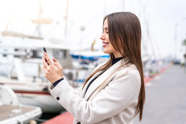 stock image Young pretty woman using mobile phone at outdoors with happy expression