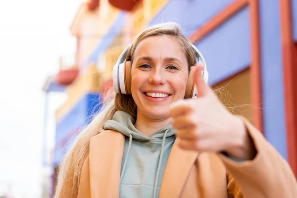 Молодая Блондинка Открытом Воздухе Слушает Музыку Большим Пальцем Вверх — стоковое фото