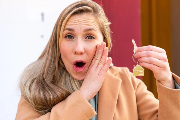 年轻的金发女人拿着家里的钥匙在外面窃窃私语 — 图库照片