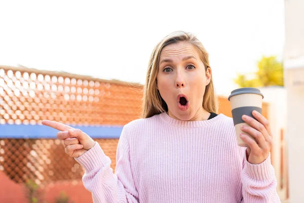 Mladá Blondýnka Žena Drží Odnést Kávu Venku Překvapen Ukazuje Stranou — Stock fotografie