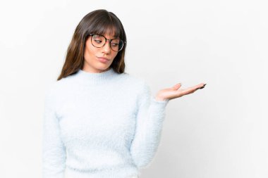 Young caucasian woman over isolated white background holding copyspace with doubts