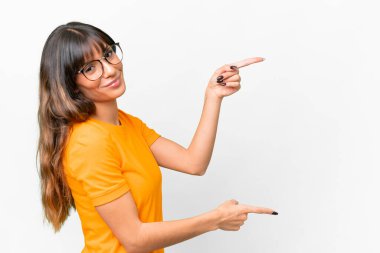 İzole edilmiş beyaz arka planda genç beyaz bir kadın parmak göstererek bir ürün sunuyor.