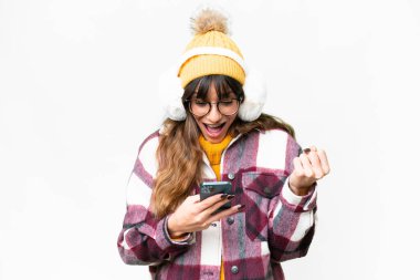 Young caucasian woman wearing winter muffs over isolated white background surprised and sending a message