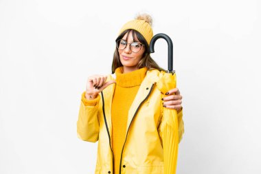 Young caucasian woman with rainproof coat and umbrella over isolated white background proud and self-satisfied