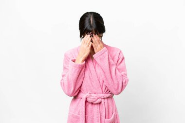 Bornozlu genç bir kadın soyutlanmış beyaz bir arka plan, yorgun ve hasta bir ifade.