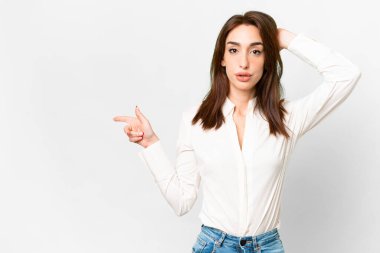 İzole edilmiş beyaz arka planda genç beyaz kadın şaşırdı ve işaret etti.