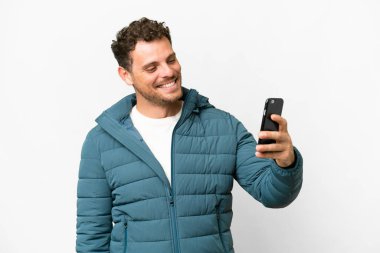 İzole edilmiş beyaz arka planı olan Brezilyalı bir adam selfie çekiyor.