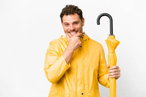 ブラジル人男性でレインプルーフコートと傘上の隔離された白い背景幸せと笑顔 — ストック写真