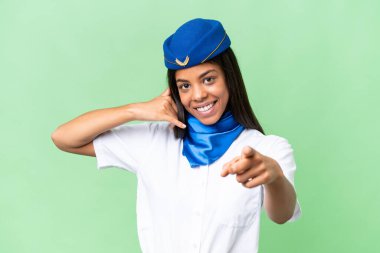 Uçak hostesi Afro-Amerikan kadın izole edilmiş arka planda telefon jesti yapıyor ve ön tarafı işaret ediyor.