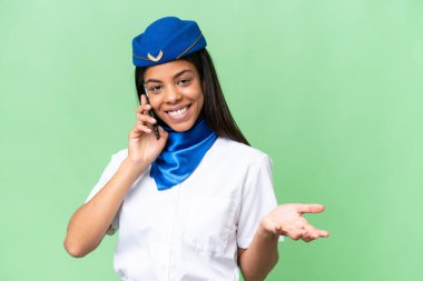 Uçak hostesi Afrikalı Amerikalı bir kadın izole edilmiş arka planda cep telefonuyla sohbet ediyor.