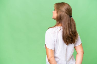 Orta yaşlı beyaz kadın izole edilmiş arka planda ve geriye bakıyor.