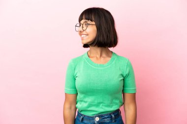 Pembe arka planda soyutlanmış genç melez bir kadın.