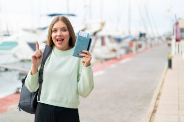 Dışarıda pasaportu olan güzel, sarışın bir kadın harika bir fikri işaret ediyor.