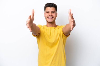 Beyaz arka planda izole edilmiş genç beyaz bir adam sunar ve davet eder.