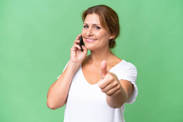 中年白种人女性在孤独的背景下 一边竖起大拇指一边和手机交谈 — 图库照片