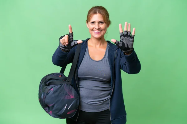 Middle-aged sport woman with sport bag over isolated background counting seven with fingers
