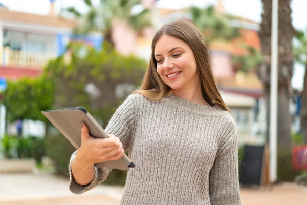 stock image Young pretty blonde woman holding a tablet at outdoors with happy expression